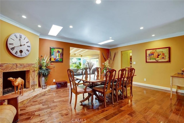 dining area featuring ornamental molding, a premium fireplace, and hardwood / wood-style floors