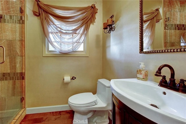 bathroom featuring vanity, a shower with door, and toilet