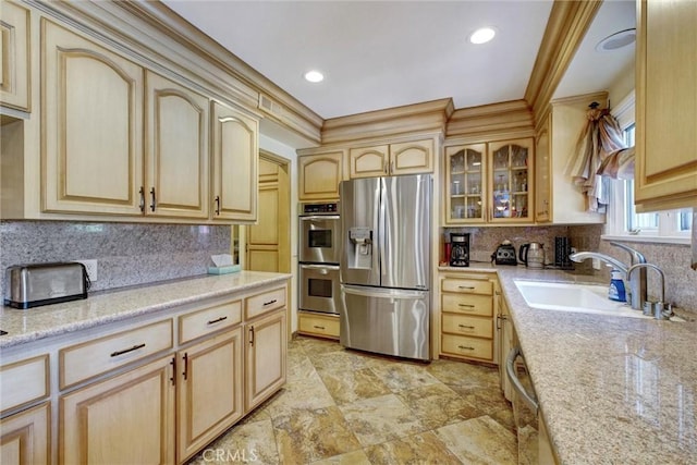 kitchen with light brown cabinetry, sink, backsplash, and stainless steel appliances