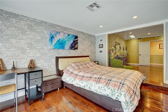 bedroom featuring crown molding, hardwood / wood-style flooring, and brick wall