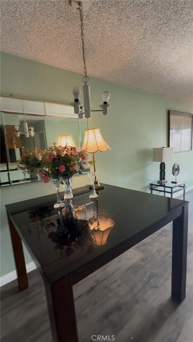 dining space with wood-type flooring and a textured ceiling