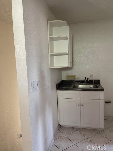 interior space featuring sink, white cabinets, and light tile patterned flooring