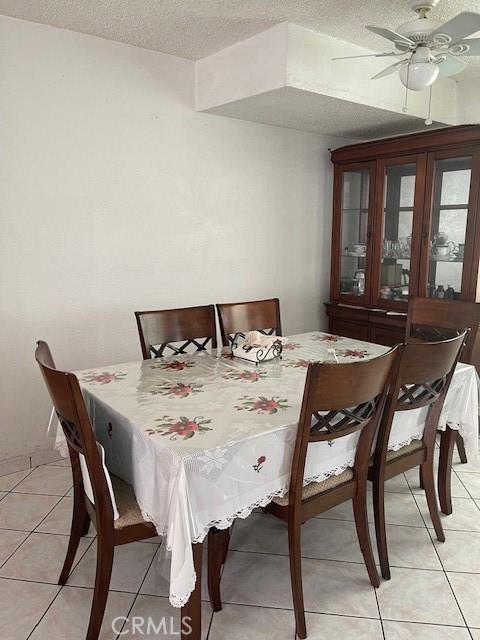 dining space featuring ceiling fan, light tile patterned floors, and a textured ceiling