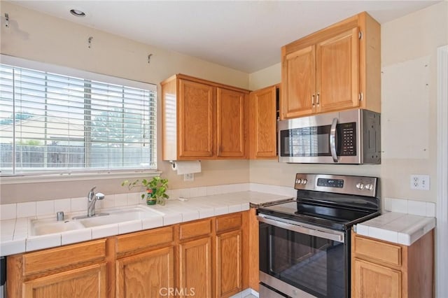 kitchen with appliances with stainless steel finishes, sink, and tile counters