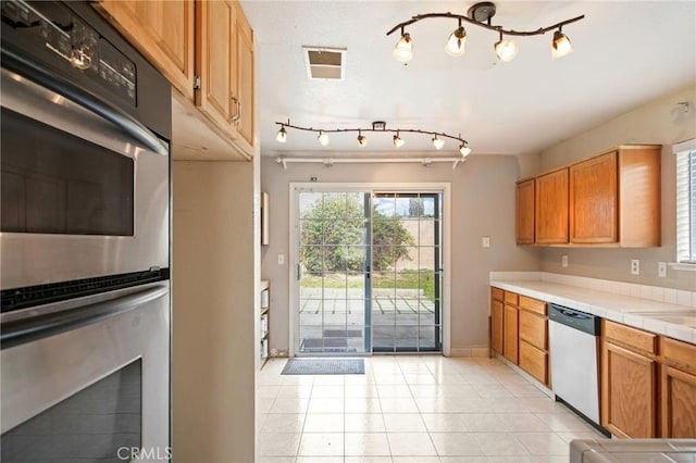 kitchen with a healthy amount of sunlight, appliances with stainless steel finishes, tile countertops, and light tile patterned floors