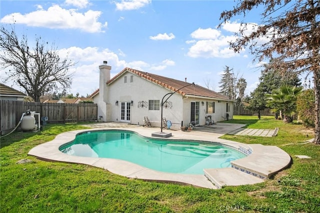 back of property featuring a fenced in pool, a lawn, a patio, and french doors