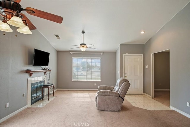 living room featuring lofted ceiling, light colored carpet, a tile fireplace, and ceiling fan