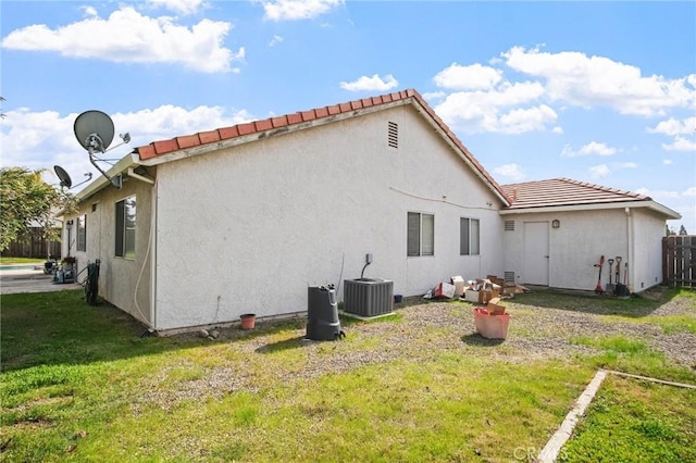 rear view of property with central air condition unit and a lawn