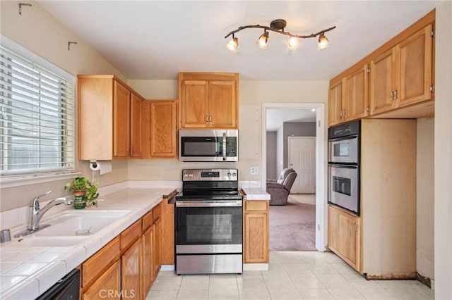 kitchen with appliances with stainless steel finishes, sink, tile countertops, and light tile patterned floors