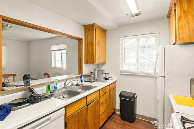 kitchen with white appliances, dark hardwood / wood-style floors, kitchen peninsula, and sink