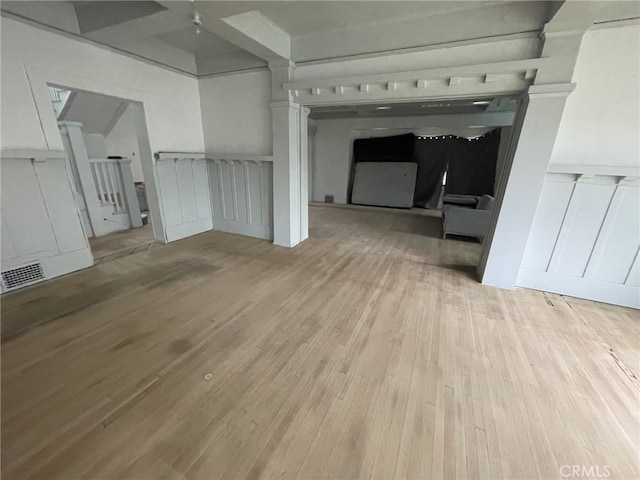 unfurnished living room with a decorative wall, wood finished floors, and visible vents