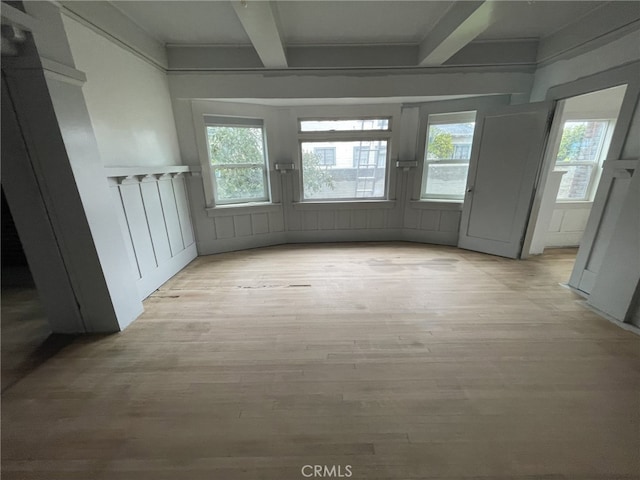 interior space featuring beam ceiling, a healthy amount of sunlight, and light wood finished floors