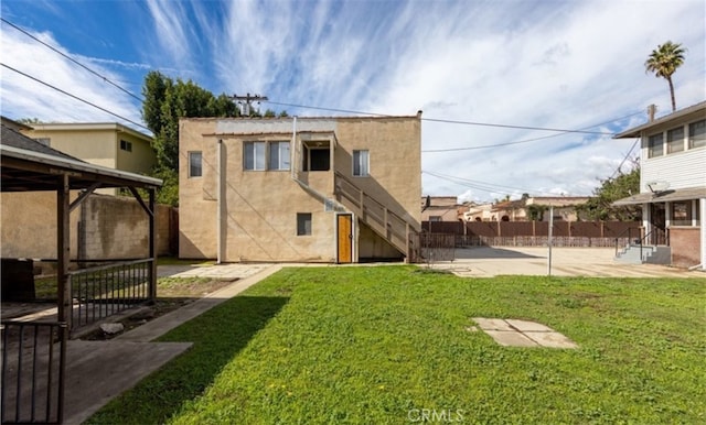 back of property featuring fence, a patio area, a lawn, and stucco siding