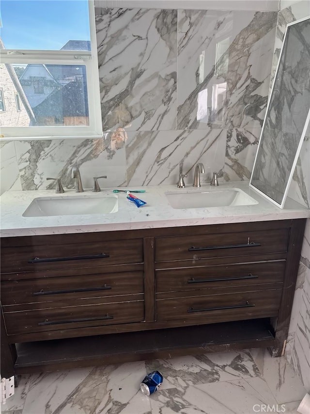 full bathroom with a sink, marble finish floor, stone wall, and double vanity