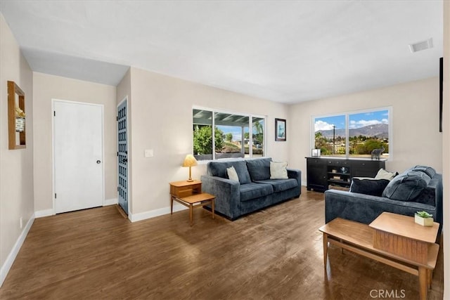 living room featuring dark wood-style flooring, visible vents, and baseboards