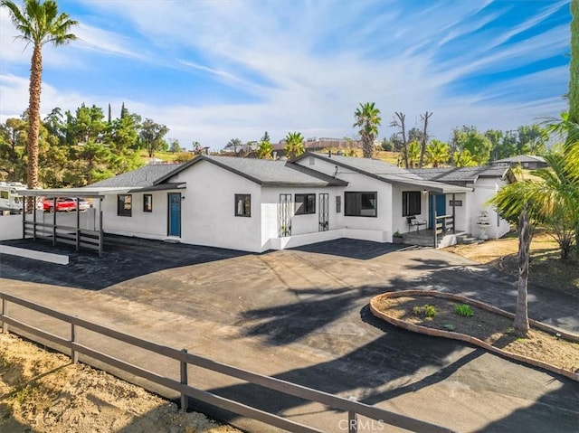 view of front of house with driveway, a shingled roof, fence, and stucco siding