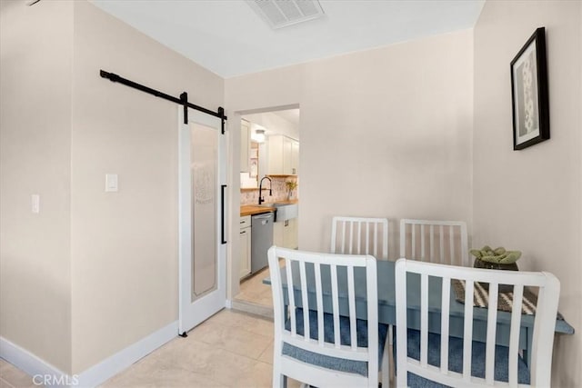 bedroom with visible vents, a barn door, connected bathroom, a sink, and baseboards