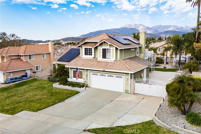 view of front of home featuring driveway, a tiled roof, a gate, a mountain view, and a front yard