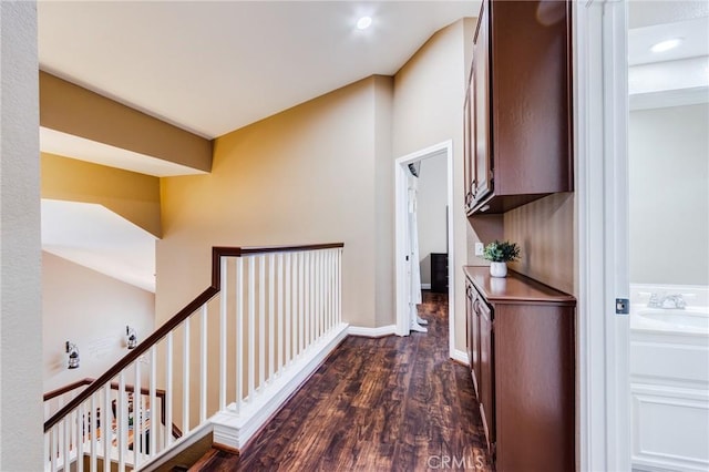 hallway featuring recessed lighting, dark wood-style flooring, a sink, and baseboards