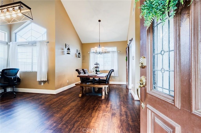 dining space featuring a chandelier, high vaulted ceiling, a barn door, wood finished floors, and baseboards