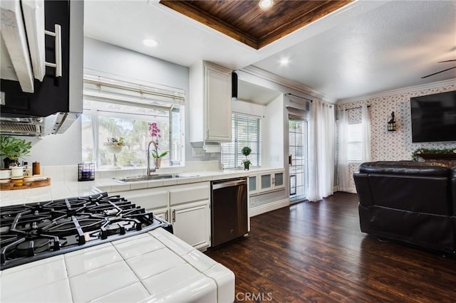 kitchen with a sink, ornamental molding, tile counters, dishwasher, and wallpapered walls