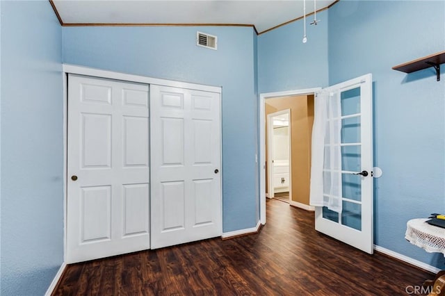 unfurnished bedroom featuring a closet, visible vents, wood finished floors, and ornamental molding