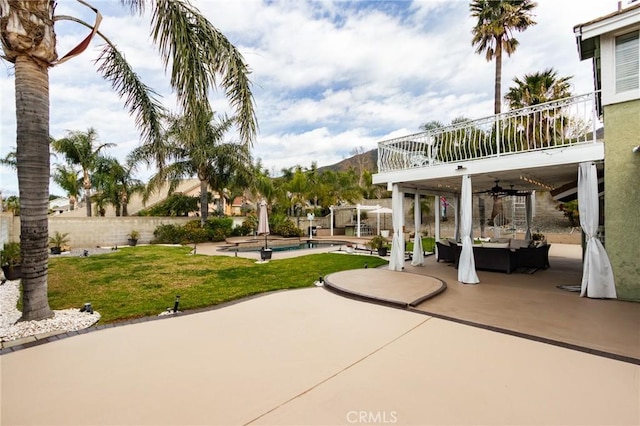 view of patio featuring a balcony, fence, a ceiling fan, an outdoor living space, and a fenced in pool