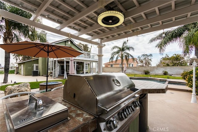 view of patio with a fenced backyard, a pool, exterior kitchen, and area for grilling