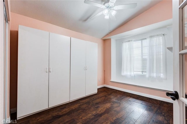 unfurnished bedroom featuring a ceiling fan, baseboards, vaulted ceiling, a closet, and dark wood-style floors