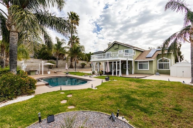 outdoor pool featuring an outbuilding, a patio, a storage shed, and a lawn