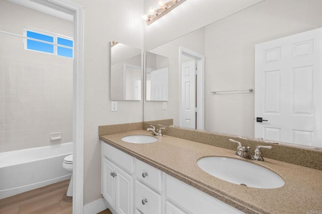 bathroom with double vanity, a sink, toilet, and wood finished floors