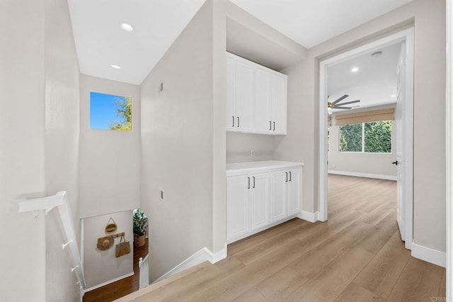 laundry room with baseboards, ceiling fan, and light wood-style floors