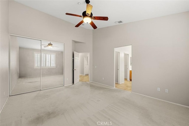 unfurnished bedroom with high vaulted ceiling, a closet, visible vents, and light colored carpet