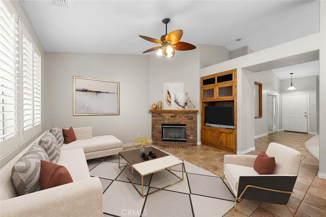 living room featuring a ceiling fan, a brick fireplace, vaulted ceiling, and light tile patterned floors