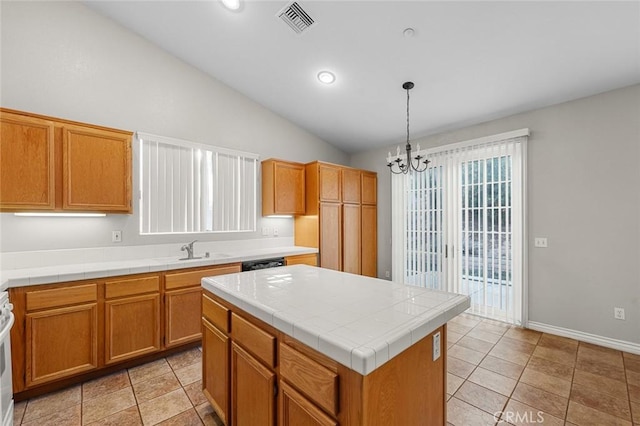 kitchen with a center island, pendant lighting, tile counters, visible vents, and a sink