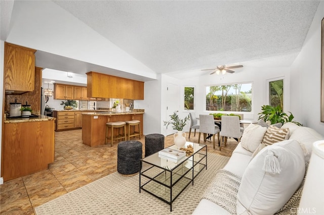 living room with ceiling fan, high vaulted ceiling, and a textured ceiling