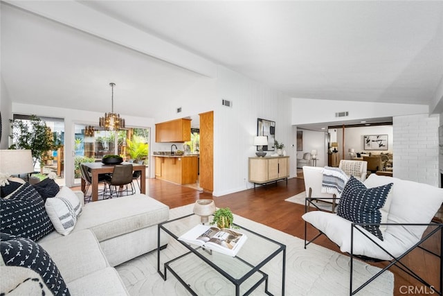 living room featuring an inviting chandelier, vaulted ceiling, and hardwood / wood-style floors