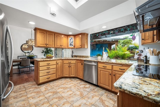 kitchen featuring sink, lofted ceiling with skylight, light stone countertops, and appliances with stainless steel finishes