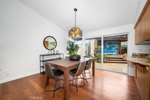 dining space with lofted ceiling, hardwood / wood-style floors, and a notable chandelier