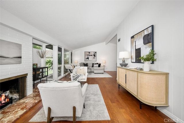 living room featuring hardwood / wood-style flooring, lofted ceiling, and a fireplace