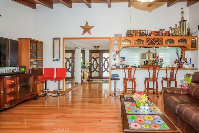 living room with a towering ceiling, light hardwood / wood-style floors, and beamed ceiling