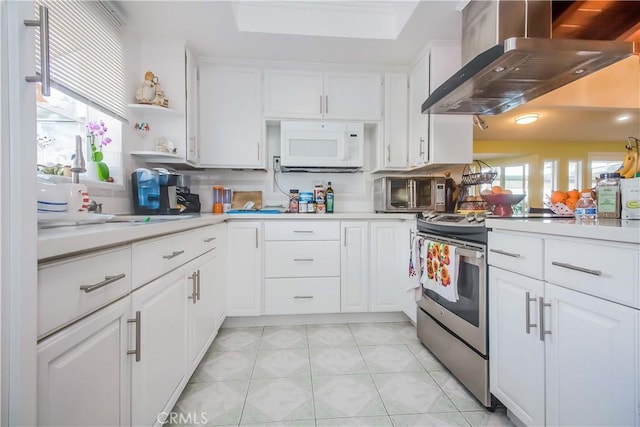 kitchen with ventilation hood, stainless steel electric range, light tile patterned floors, decorative backsplash, and white cabinets