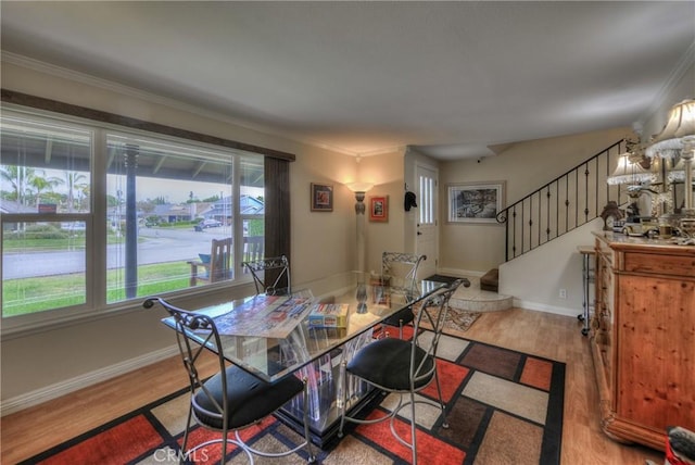 dining space with ornamental molding and light hardwood / wood-style floors