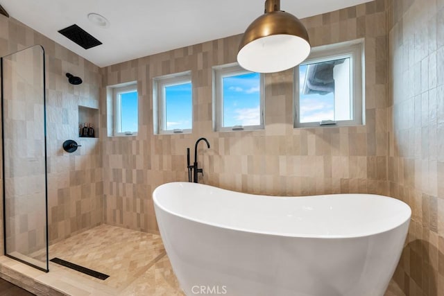 bathroom with tile walls and shower with separate bathtub