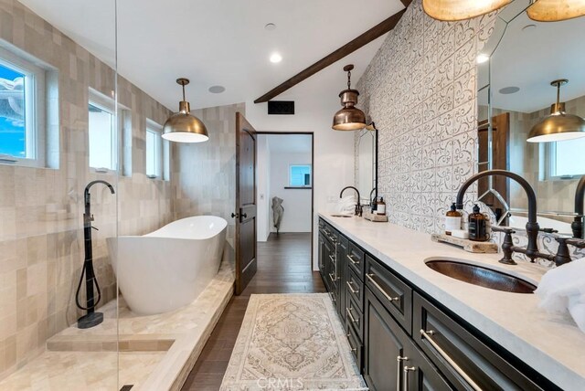 bathroom with a bathing tub, a wealth of natural light, vanity, and tile walls