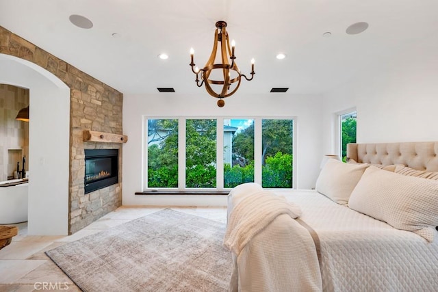 bedroom featuring a notable chandelier and a stone fireplace