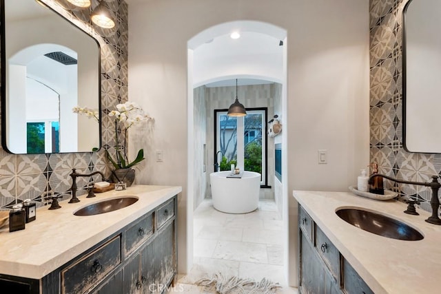 bathroom featuring tasteful backsplash, vanity, and a tub to relax in