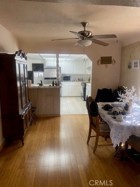 interior space with stainless steel appliances, ceiling fan, a textured ceiling, and light hardwood / wood-style floors