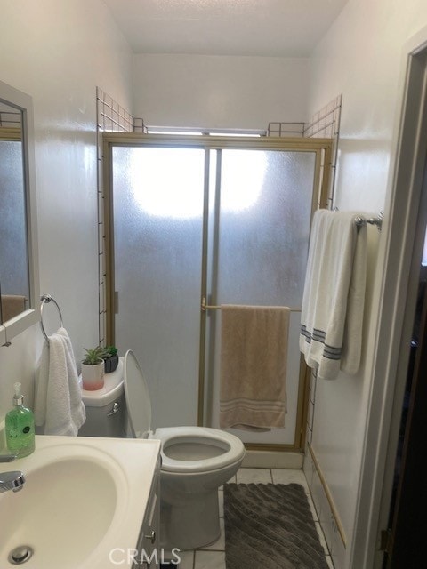 bathroom with vanity, tile patterned floors, toilet, and walk in shower