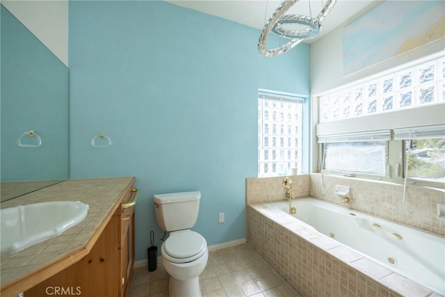 bathroom featuring vanity, tile patterned floors, toilet, baseboards, and a jetted tub